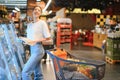 Smiling happy woman enjoying shopping at the supermarket, she is leaning on a full cart Royalty Free Stock Photo