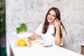 Smiling happy woman having a relaxing healthy breakfast at home sitting at kitchen table eating cereals wtih fruit and yogurt Royalty Free Stock Photo