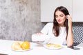 Smiling happy woman having a relaxing healthy breakfast at home sitting at kitchen table eating cereals wtih fruit and yogurt Royalty Free Stock Photo