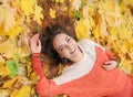 Smiling happy woman portrait, laying in autumn leaves