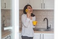 smiling happy woman talking no phone drinking tea from yellow mug at the kitchen Royalty Free Stock Photo