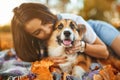 Smiling happy woman together with Welsh Corgi Pembroke dog in a park outdoors. Young female owner huging pet in park at