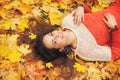 Smiling happy womanl portrait, lying in autumn leaves