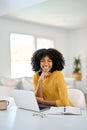 Happy young African woman sitting at home table looking at camera with laptop. Royalty Free Stock Photo