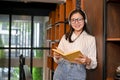 Smiling and happy young Asian female college student in a campus library or bookstore Royalty Free Stock Photo