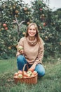 smiling happy young blonde Caucasian woman on apple farm with wicker basket full of fruits