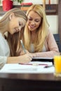 Young woman helping her teenage daughter with homework and studying during pandemic lock-down