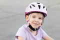 Smiling happy young child, a girl wearing a pink safety helmet with straps fastened, kid cyclist biker portrait, face closeup, Royalty Free Stock Photo