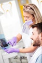 Happy young female dentist showing x-ray images to patient