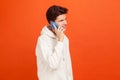 Smiling happy young man in casual style hoodie holding phone near ear, talking with girlfriend, flirting, good connection Royalty Free Stock Photo