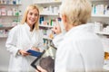 Smiling happy young and mature female pharmacists working behind the counter in a pharmacy