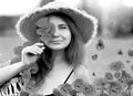 Smiling and happy young red-haired  woman in a black dress and a hat holding red poppies near the face. Beautiful poppy field at Royalty Free Stock Photo