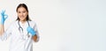 Smiling healthcare worker, asian woman doctor in rubber gloves and medical uniform, shows approval, okay sign, white Royalty Free Stock Photo