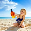 Smiling healthy child in swimwear on seacoast showing lotion