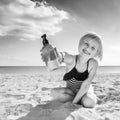 Smiling healthy child in swimwear on seacoast showing lotion Royalty Free Stock Photo