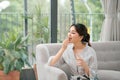 Smiling healthy young woman holding pill glass of water sit on sofa at home