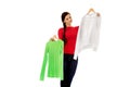 Smiling hesitant young woman holding two shirts