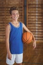 Smiling high school boy holding a basketball in the court