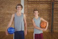 Smiling high school boys holding basketball in the court