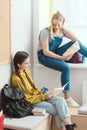 Smiling high school female students with books talking to