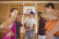 Smiling high school kids and their coach standing in the basketball court