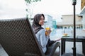 smiling hijab girl showing juice sitting by the pool Royalty Free Stock Photo