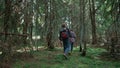 Smiling hikers walking in forest. Couple of tourists trekking between trees Royalty Free Stock Photo