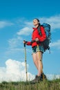 Smiling hiking young woman standing on a green meadow