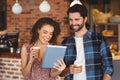 Smiling hipster couple with take-away cups using tablet Royalty Free Stock Photo