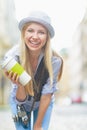 Smiling hipster girl with cup of hot beverage on city street Royalty Free Stock Photo