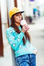 Smiling hipster girl with cup of hot beverage on Royalty Free Stock Photo