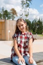 Smiling hipster girl sitting on bench in the city park. Royalty Free Stock Photo