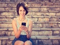 Smiling Hipster Girl Texting with Her Mobile Phone Royalty Free Stock Photo