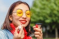 Smiling hipster happy woman doing make-up using lipstick and mirror outdoors Royalty Free Stock Photo