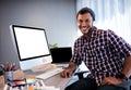 Smiling hipster man posing for camera at computer desk in studio Royalty Free Stock Photo