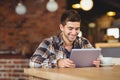 Smiling hipster sitting and using tablet computer Royalty Free Stock Photo