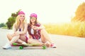 Smiling hipster teenage friends with skateboard, colorised image with sunflare