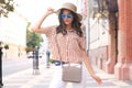 Smiling hipster trendy girl posing at the city summer street,holding hat Royalty Free Stock Photo