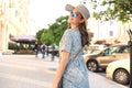 Smiling hipster trendy girl posing at the city summer street,holding hat Royalty Free Stock Photo