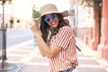 Smiling hipster trendy girl posing at the city summer street,holding hat Royalty Free Stock Photo