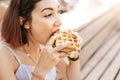 Hipster woman eating a delicious sandwich with a loaf of a checkered Viennese waffle. Modern Street food concept Royalty Free Stock Photo