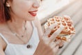 Hipster woman eating a delicious sandwich with a loaf of a checkered Viennese waffle. Modern Street food concept Royalty Free Stock Photo