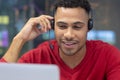 Smiling hispanic businessman talking through headset while looking at laptop in modern workplace Royalty Free Stock Photo