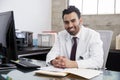 Smiling Hispanic male doctor sitting at desk, portrait Royalty Free Stock Photo