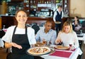 Smiling hispanic waitress welcoming in cozy pizza restaurant