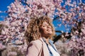 Smiling hispanic woman with eyes closed in park enjoying sunny day. Spring flowers background Royalty Free Stock Photo