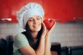 Cheerful chef Holding a Heart Shaped Tomato in the Kitchen Royalty Free Stock Photo