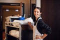 A smiling hotel maid with cleaning cart and cleaning supplies, l Royalty Free Stock Photo