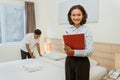 Smiling household manager with clipboard note on background hotel room Royalty Free Stock Photo