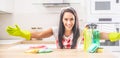 Smiling housekeeper holding her arms wide open in the kitchen, with colorful rags and detergents on the desk